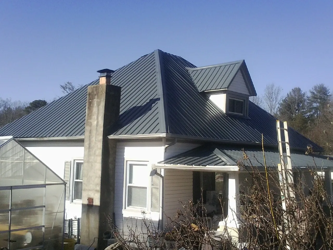 Dark blue standing seam metal roof on a white farmhouse with dormer — Slate & Tile Roof Repair by Roofing Brothers in Saugerties