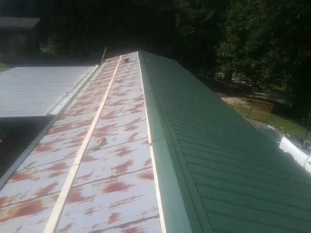 Old rusted panels beside newly installed green metal roofing — Wind Damage Roof Repair by Roofing Brothers in Saugerties