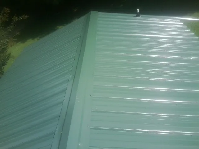 New green metal panels meeting at the ridge of a roof — Flat Roof Repair work by our crew in Saugerties