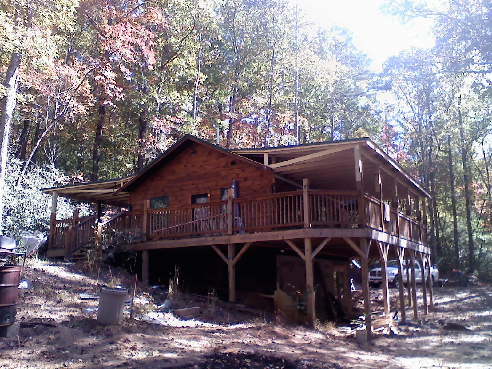 Log cabin with a wraparound porch and metal roof in the fall in Saugerties
