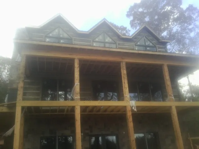 Dormers and porch framing on a large log home under construction — Roof Coating work by our crew in Saugerties