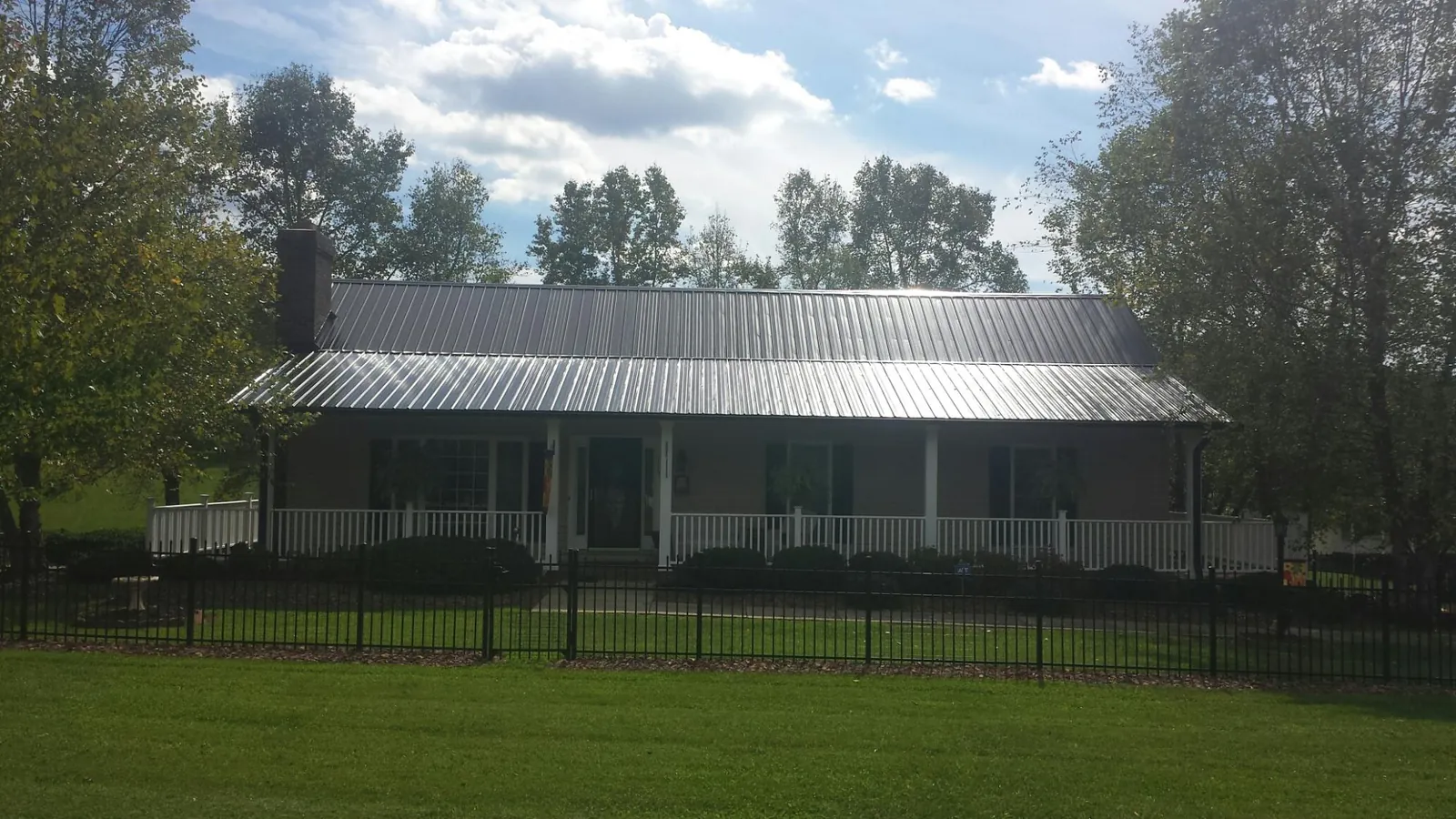 Gray metal roof on a brick ranch with a full width front porch — Gutter Guard Installation work by our crew in Saugerties