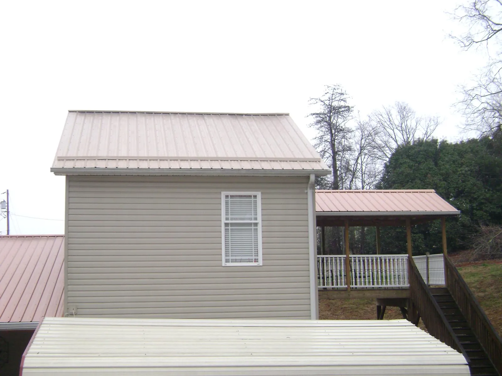 Tan metal roofs on a two story addition and attached porch, from a Roof Replacement job in Saugerties