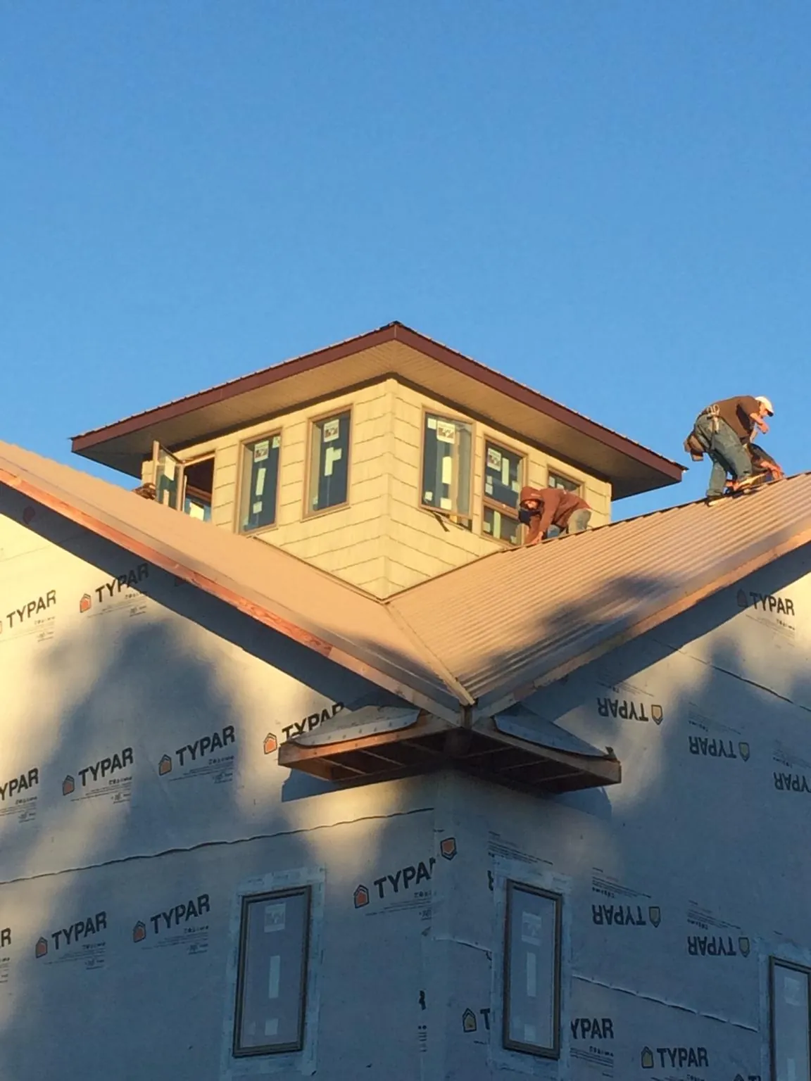 Roofers working around a rooftop cupola on a new metal roof at sunset — Roof Waterproofing in Saugerties by Roofing Brothers